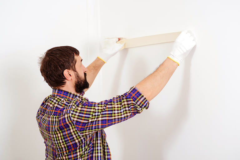 Painter man at work. Skillful and professional painter. Construction and renovation. Home renovations service. Painter using masking tape before painting. Painters work.