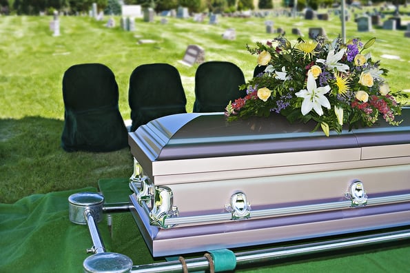Image of a steel Casket with Flowers on top in a cemetery