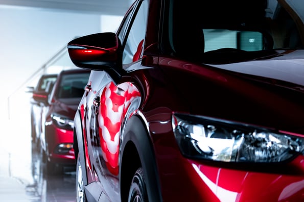 Red SUV car parked in modern showroom. New and luxury SUV compact car. Car dealership concept. Automotive industry. Automobile leasing business. Front view of red shiny car parked in showroom.