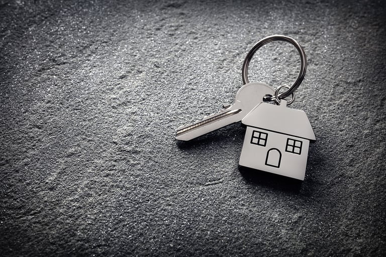 House key on a house shaped keychain on stone concept for real e