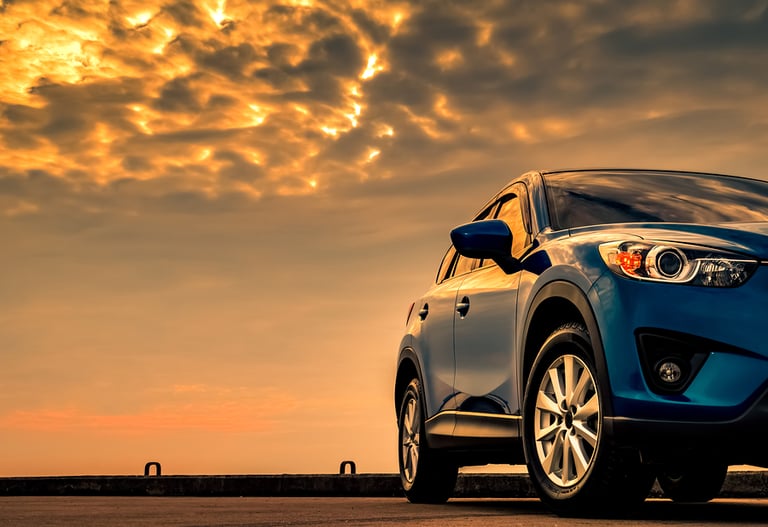 Blue compact SUV car with sport and modern design parked on concrete road by the sea with beautiful sunset sky. Hybrid and electric car technology concept. Car parking space. Automotive industry.