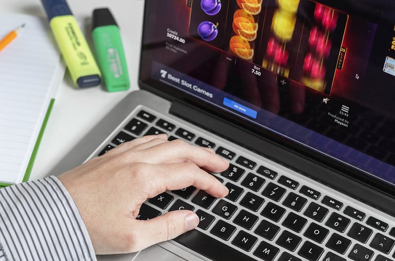 laptop London / UK - August 14th 2019 - Online gambling at the workplace, person at a computer keyboard playing fruit machine slots