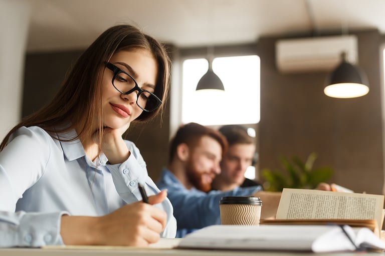 Smart girl student studying at library, writing essay and drinking coffee, free space