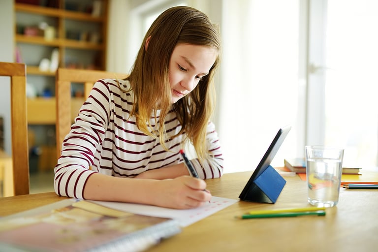 Professional Research Preteen schoolgirl doing her homework with digital tablet at home. Child using gadgets to study. Education and distance learning for kids. Homeschooling during quarantine. Stay at home entertainment.