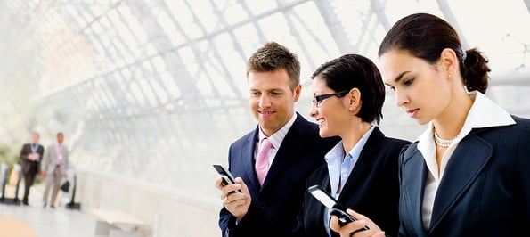 Happy businesspeople using mobile phones at office lobby - plenty of copyspace.