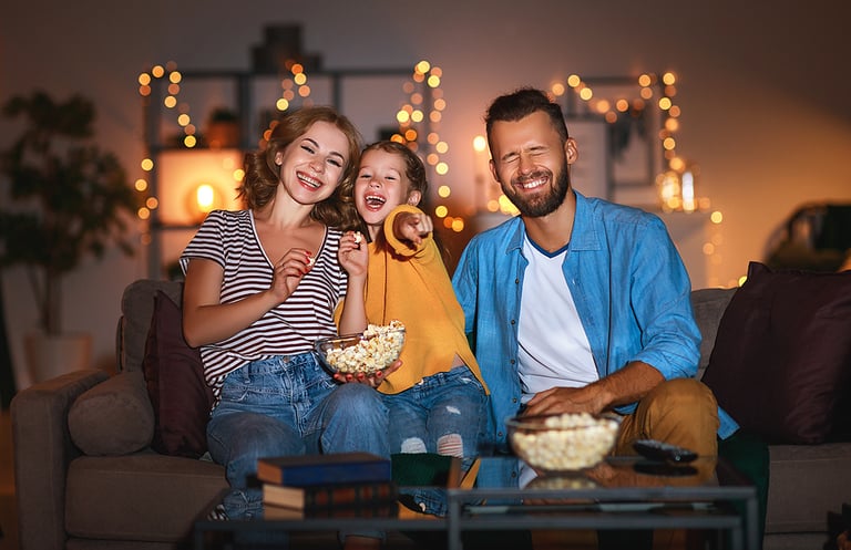 family mother father and child daughter watching projector, TV, movies with popcorn in the evening at home