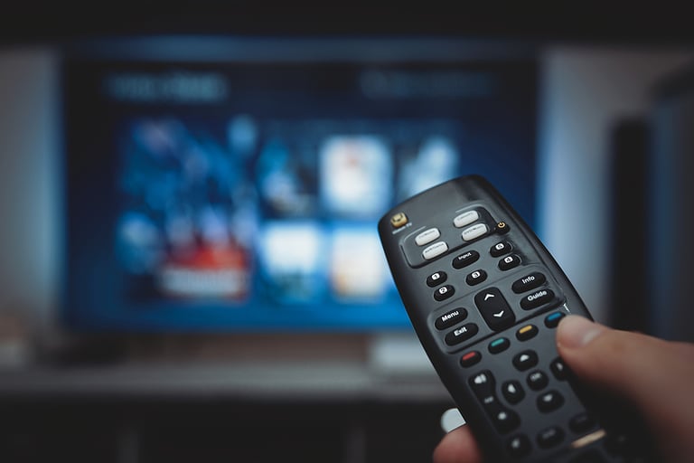 Online VOD service on television. Man watching TV, streaming service, video on demand, remote control in hand.