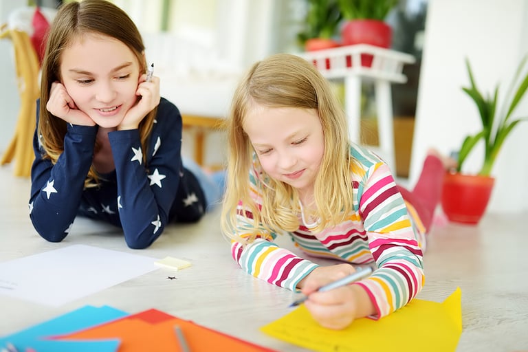 Two young sisters drawing with colorful pencils at home. Creative kids doing crafts together. Education and distance learning for kids. Homeschooling during quarantine. Stay at home entertainment.