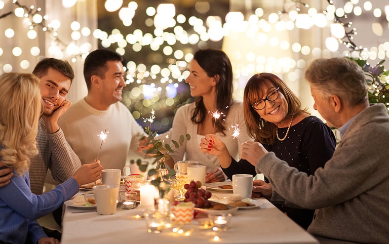 celebration, holidays and christmas concept - happy family with sparklers having fun at dinner party at home