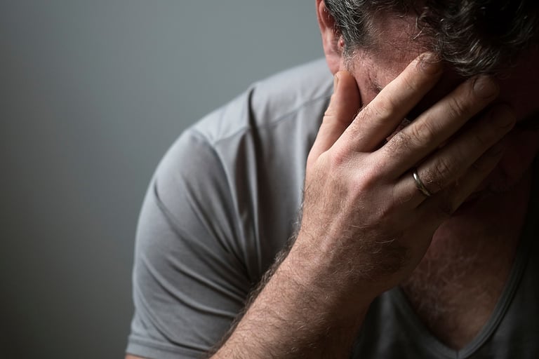 Unhappy sad man in depression covered his face with his hand
