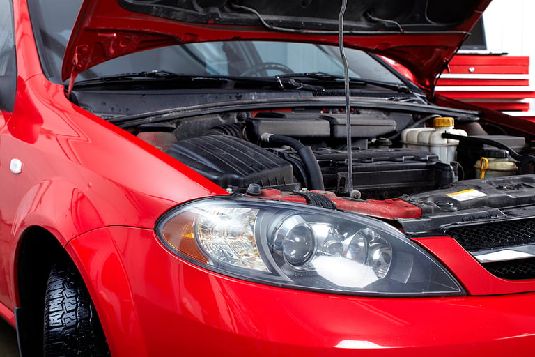 Car with open hood in auto repair shop.
