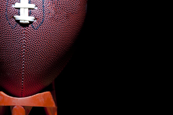 close up of an american football against a black background