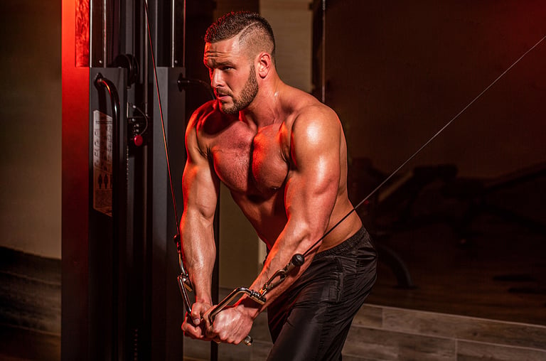 Fitness man execute exercise with exercise-machine Cable Crossover in gym. Handsome man with big muscles in gym. Machine in the gym. Muscular man working out in gym doing exercises at triceps, strong male naked torso abs steroids