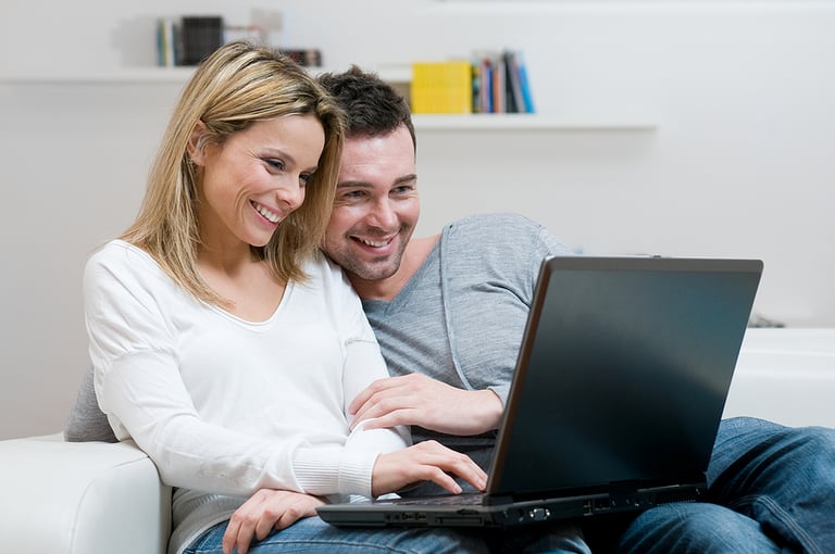 Young couple relaxing on the couch with laptop in their living r