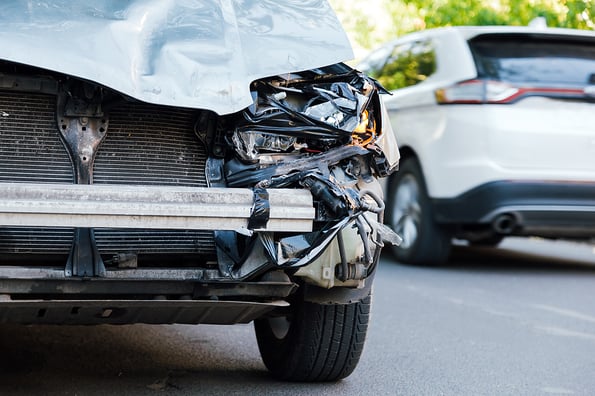Destroyed car in car crash traffic accident on city road. Smashed broken front auto headlight, dented hood no bumper on gray SUV car in car accident. Auto life health insurance.