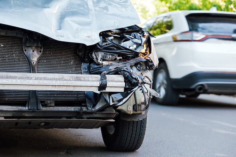 Destroyed car in car crash traffic accident on city road. Smashed broken front auto headlight, dented hood no bumper on gray SUV car in car accident. Auto life health insurance.