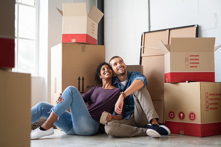 Young couple resting after moving into a new home and daydreaming. Multiethnic contemplative couple sitting on floor and thinking while looking up. Happy couple buy new apartment and plan a family.