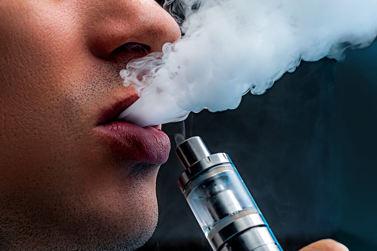 Close-up - young man vaping e-cigarette. New popular vaping device. Vapour, Vaping Concept