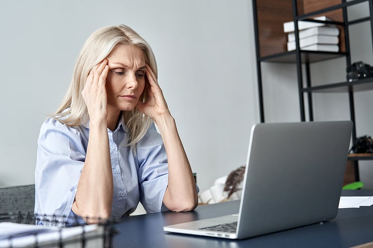 trauma Stressed forgetful old middle aged business woman suffering from headache after computer work. Tired upset 50s lady massaging head feeling stress, fatigue or migraine using laptop at home office.