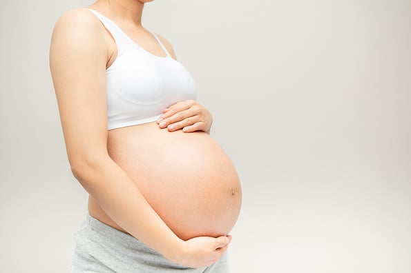 Pregnant woman touching her big belly. Close up. Motherhood, pregnancy, people and expectation concept. Pregnant woman expecting baby