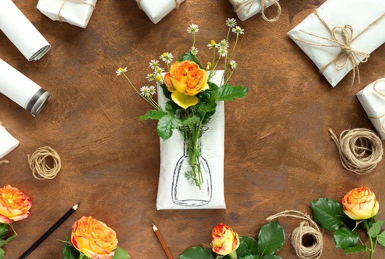 Set of wrapping paper and flowers for handmade on gold background. Homemade craft box gifts with painted vase and bouquet of yellow roses and delicate daisies. nn Flat lay, top view concept with copy space for text. wine
