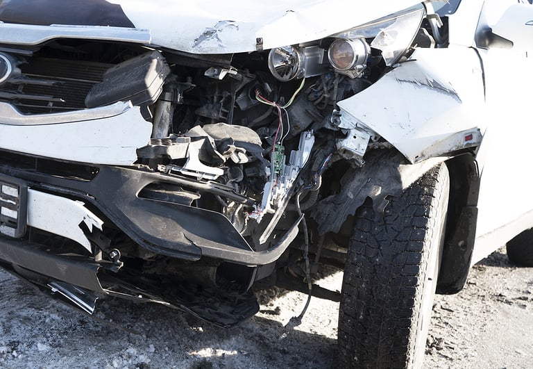 A white car crashed accident. Car accident on the road. Car crash accident on street. Damaged vehicle. Car insurance concept. White color vehicle get big damage by accident on the road.