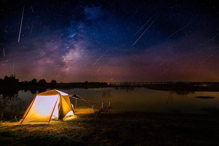 camping lantern Traveling and camping concept - camp tent at night under a sky full of stars. Orange illuminated tent. Beautiful nature - field, forest, plain. Moon and moonlight