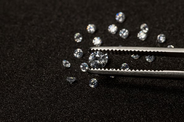 Diamonds are valuable, expensive and rare. For making jewelry. brilliant cut diamond held by tweezers. Beautiful diamond stone in tongs
