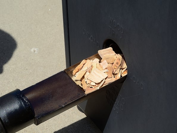 Putting Hickory Wood Chips in a Barbecue BBQ Smoker
