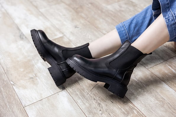 Beautiful female legs with fashionable black boots on the background in the studio. Women's stylish leather boots. winter boots
