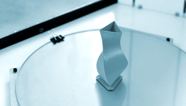 Bright blue object printed by 3d printer on 3d printer inside.