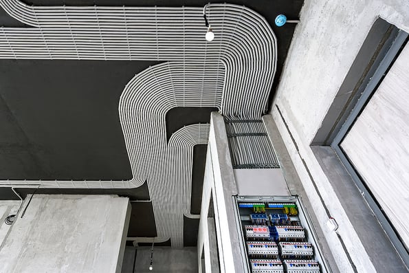 Electrical cables and switch box on house concrete ceiling and wall. Modern plastic hoses with wires in room. Lines of pvc wiring tubes after professional work. Renovation of home or factory interior