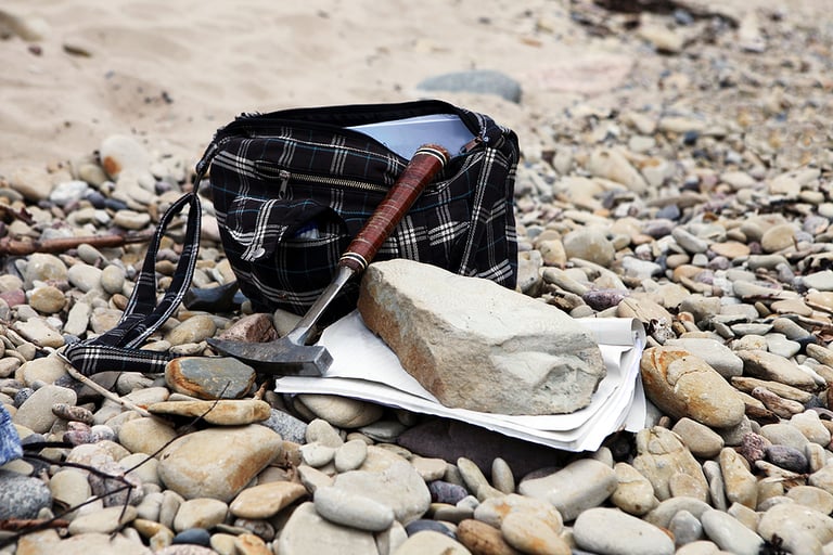 Geologists bag with the stones and notes papers and hammer. Geology science concept. The geologists hammer and mineral are laid out on a pebbels