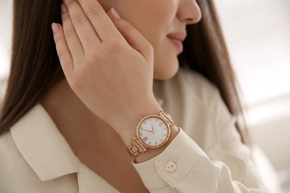 Woman with luxury wristwatch on blurred background, closeup