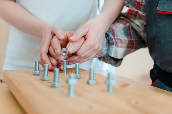 Closeup on hand of man in occupational therapy screwing nut on bolt