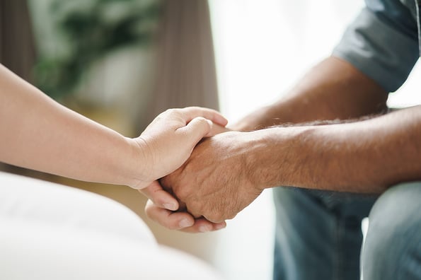 Female friend or family sitting and hold hands during cheer up to mental depress man, Psychologist provides mental aid to patient. PTSD Mental health concept