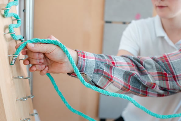 Man in occupational therapy with therapist training his dexterity at the rope board