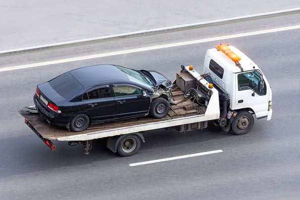 Wrecked car after an accident on a tow truck transported on a highway