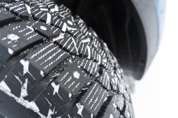 Car tire in the snow close up. Car tracks on the snow. Traces of the car in the snow. Winter tires. Tyres covered with snow at winter road. Winter road safety concept