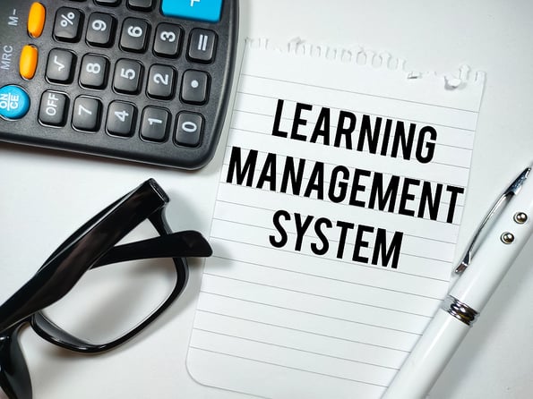 Education concept.Text LEARNING MANAGEMENT SYSTEM writing on notepaper with pen,calculator and glasses on white background.