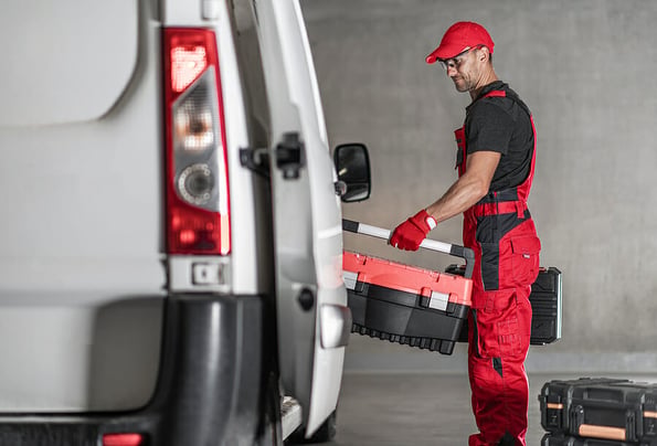 Smiling Caucasian Contractor Worker in his 40s Loading His Tool Boxes To His Commercial Van. Business Vehicles Theme.