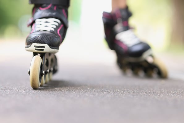Woman is rolling on black beautiful rollerblades on asphalt closeup
