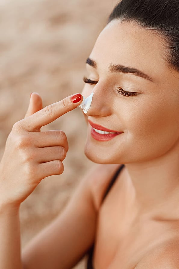Suncream. Beautiful Woman Face Portrait Beauty Skin Care Concept. Suntan Lotion Beautiful Woman Applying on beautiful on Face. Sunscreen Solar Cream. Sun protection