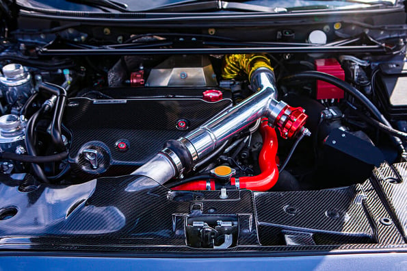Car under hood showing high performance transverse engine with tuning and modification, red, yellow, silver, chrome and carbon fiber clean parts