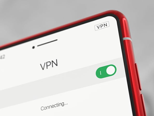 Red smartphone with VPN enabled, close-up. Modern cell phone with VPN, on a light background. Using a VPN on a smartphone. Selected focus