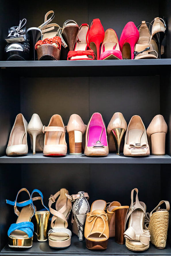 Gray closet shelves full of fashion female shoes on heels pair storage organization of cupboard