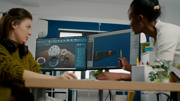 Diverse women game software developers creating game interface sitting in startup creative agency company using pc with two displays. Workers developing online video games with modern technology