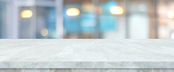 Empty white table top, counter, desk over blur perspective store with bokeh light background, White marble stone table, shelf and blurred shop for food, product display mockup, template backdrop, banner, Retail business wallpaper, poster