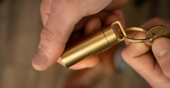 Person holding a small brass tube attached to house key