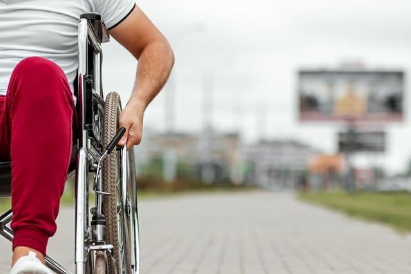 A disabled man sits in a wheelchair on the street. The concept of a wheelchair, disabled person, full life, paralyzed, disabled person, health care